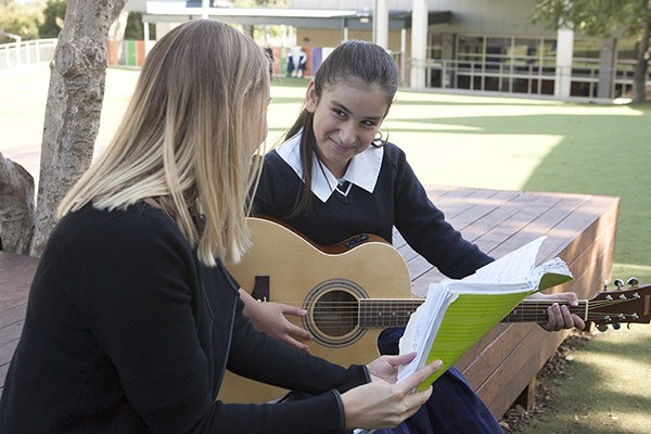 teacher teaching student how to play guitar